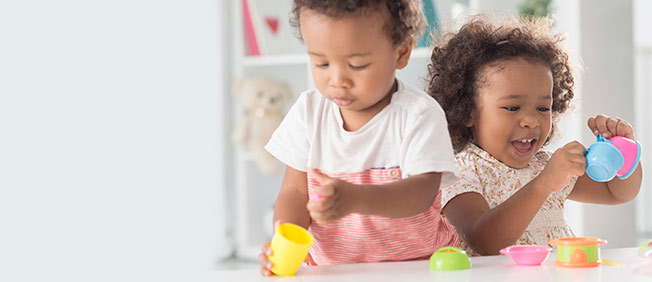 Two toddlers playing with tea set